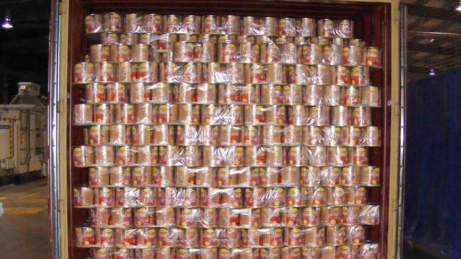 A customs agent unpacks canned tomato tins holding tonnes of ecstasy tablets. Picture: Australian Customs Service.