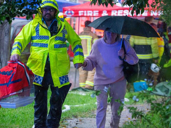 Police escorting a neighbour of building explosion on Waikanda Cres. Picture: Thomas Lisson