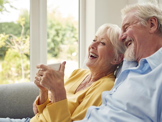 Retired Senior Couple Sitting On Sofa At Home Drinking Coffee And Watching TV Together;   Retirees retirement generic.