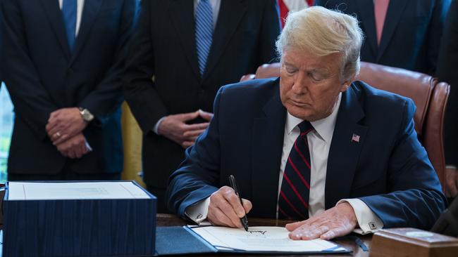 Donald Trump signs the US coronavirus stimulus relief package on March 27. Picture: AP