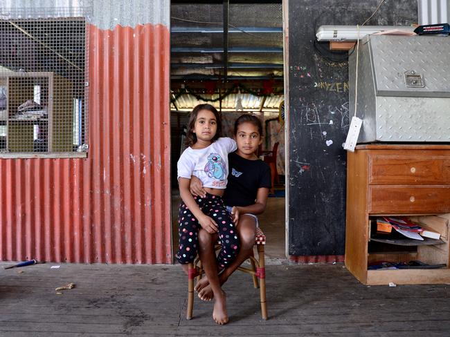 Selena Fourmile, 8, sits with her sister Alicia, 10, outside the door of their dilapidated Yarrabah home. Picture: Isaac McCarthy