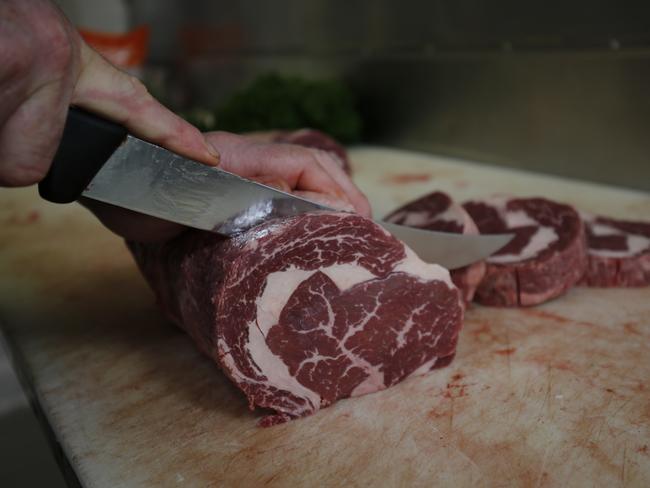 Mr Dumbrell cuts some grass fed wagyu beef. Picture: Simon Baker