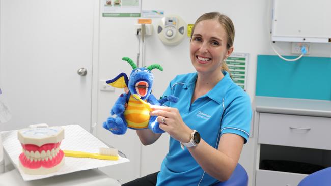 Cairns and Hinterland Health and Hospital Service oral health team leader Stephanie Wallace demonstrates how to brush teeth on a dragon prop, to help children understand the importance of oral hygiene. Photo: Catherine Duffy.