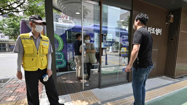 A man, right, checks his temperature in front of a thermal imaging camera to enter a shelter booth at a bus stop in Seoul on Wednesday. Picture: AFP