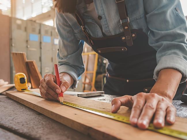 TRADESMAN/ TRADIE/BUILDING INDUSTRY: Carpenter working with equipment on wooden table in carpentry shop. woman works in a carpentry shop.