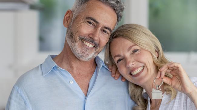 Mature couple with the key to their new house. They are happy and smiling. The kitchen can be seen in the background. Home housing unlocking equity generic