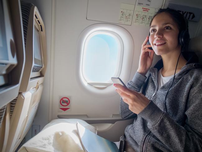 Woman in airplane, wearing headphones. Picture: iStockTravel wisdom headphones, Jennifer Dudley