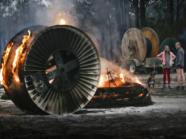 East Gippsland fires Mallacoota township. Destroyed homes in the township. Jessica Tregellas aged 12 and her sister Emily aged 15 walk their dog amongst burning NBN cable rolls.    Picture: David Caird