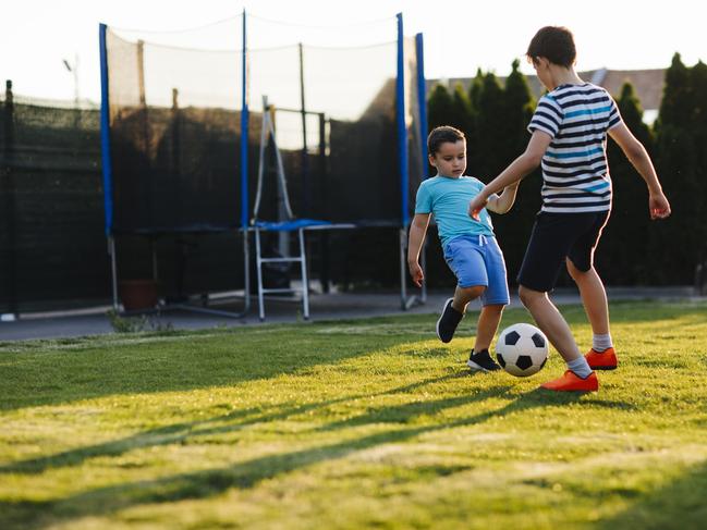 Brothers playing soccer in their backyard