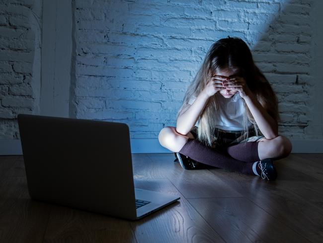 Scared sad girl bullied on line with laptop suffering cyberbullying and harassment feeling desperate and intimidated. Child victim of bullying stalker social media network