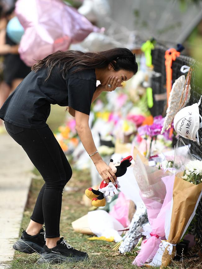 A woman holds back tears as she places a Minnie Mouse doll at a memorial for the four children. Picture: AAP