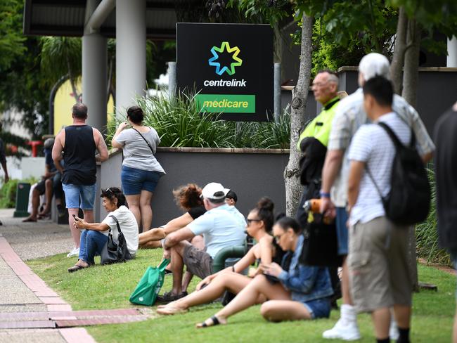 People are seen in long queues outside the Centrelink office in Southport on the Gold Coast, Monday, March 23, 2020. Centrelink offices around Australia have been inundated with people attempting to register for the Jobseeker allowance in the wake of business closures due to the COVID-19 pandemic.  (AAP Image/Dan Peled) NO ARCHIVING