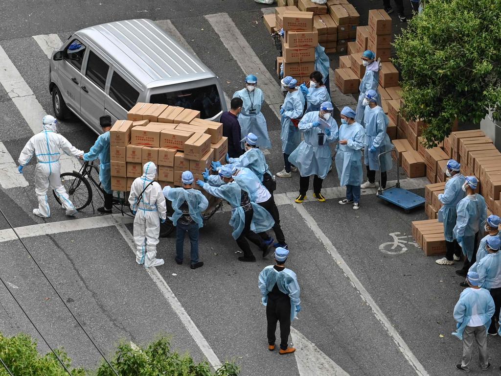 Workers push a cart full of boxes with food in locked-down Shanghai. Picture: Hector Retamal/AFP