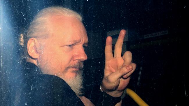 LONDON, ENGLAND - APRIL 11: Julian Assange gestures to the media from a police vehicle on his arrival att Westminster Magistrates court on April 11, 2019 in London, England.  After weeks of speculation Wikileaks founder Julian Assange was arrested by Scotland Yard Police Officers inside the Ecuadorian Embassy in Central London this morning. Ecuador's President, Lenin Moreno, withdrew Assange's Asylum after seven years citing repeated violations to international conventions. (Photo by Jack Taylor/Getty Images)