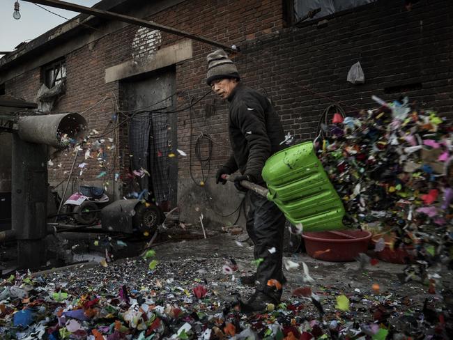 A Chinese worker shovels plastic after it is chopped into small pieces before being recycled