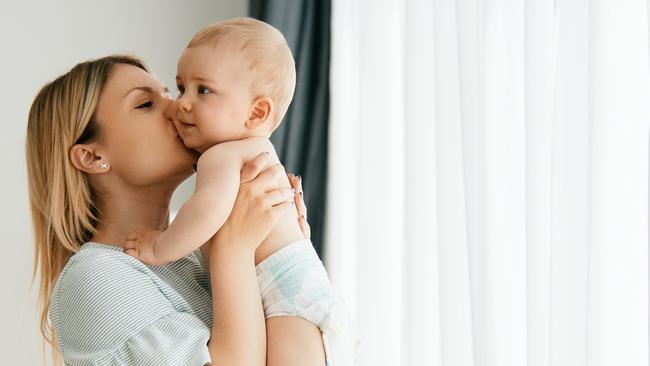 Young affectionate mother holding her baby boy and kissing him at home. Copy space. istock image