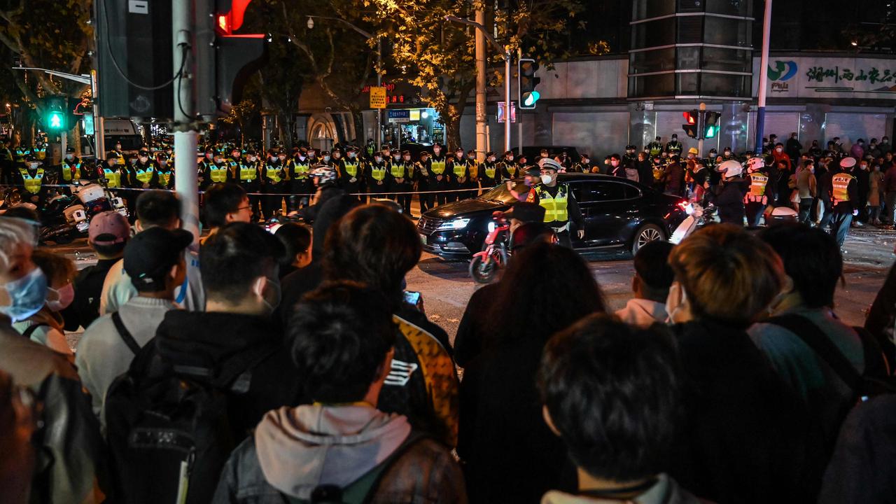 People gather as police officers block Wulumuqi street. Picture: Hector Retamal/AFP