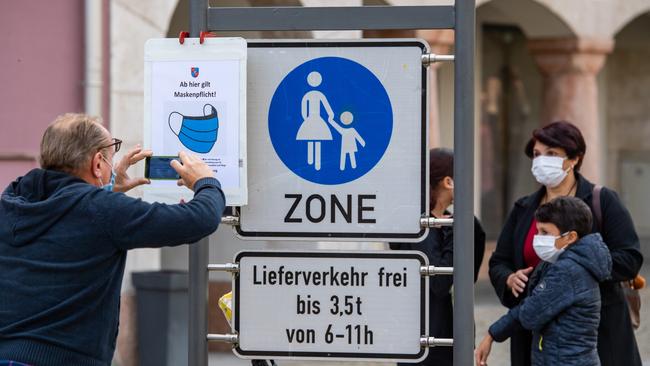 A man wearing a face mask takes a picture of a sign in Berchtesgaden, Germany, saying: ‘From here face mask mandatory!’ Picture: Getty Images