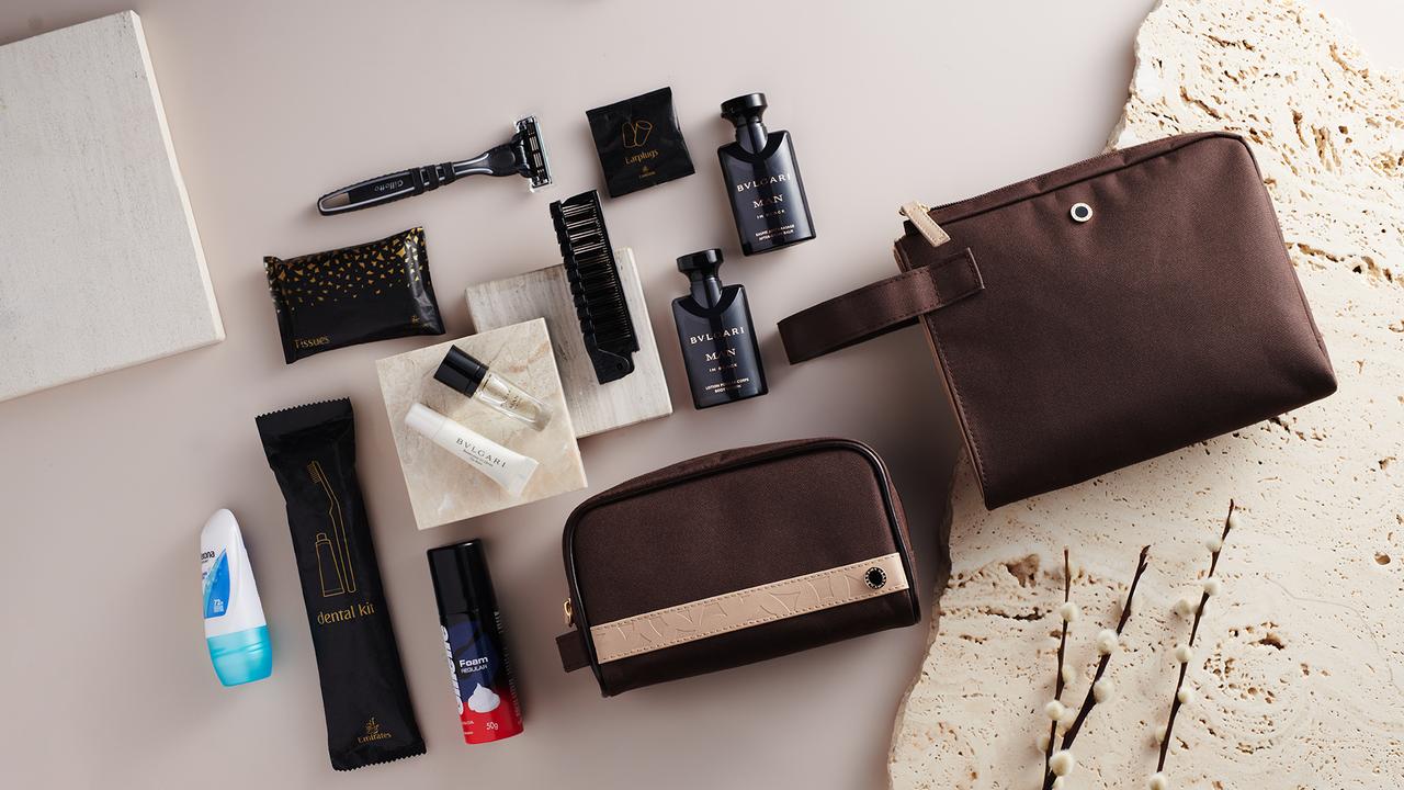 The masculine business class offering features two contemporary chestnut brown fabric bags with cream faux leather accents, in a handheld style and a classic toiletry bag silhouette.