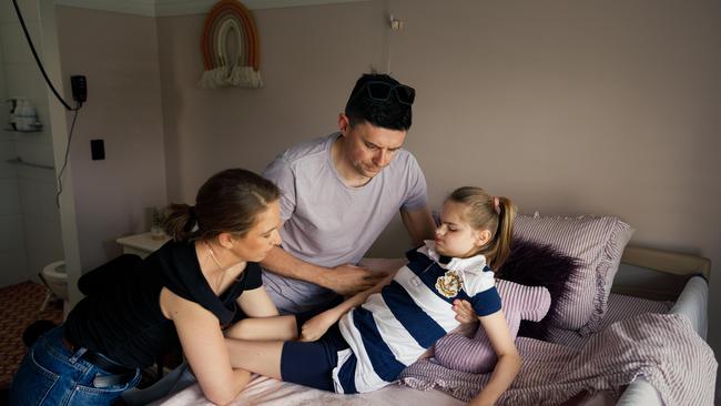 Josie’s parents, Sara and Scott, lift her into her bed at the family’s home. Picture: Max Mason-Hubers