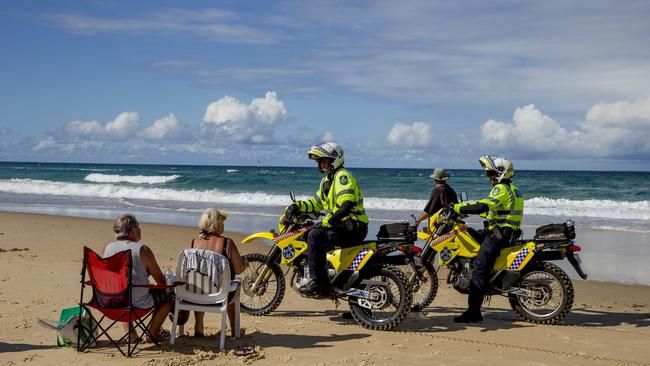 Gold Coast police officers speaking to beachgoers sunbathing at Surfers Paradise. Beach goers are only allowed to exercise in the COVID-19 crisis. Picture: Jerad Williams