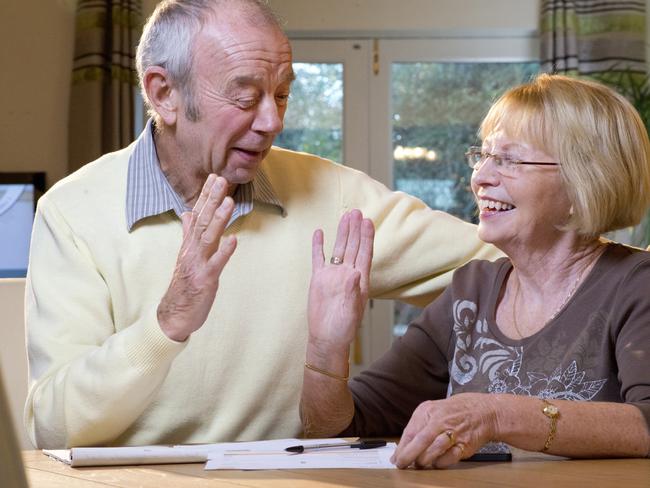 senior couple sorting finances; happy retirees high-five money and superannuation generic