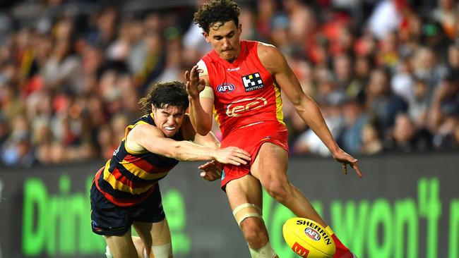 GOLD COAST, AUSTRALIA - JUNE 19: Wil Powell of the Suns is tackled while kicking the ball during the round 14 AFL match between the Gold Coast Suns and the Adelaide Crows at Metricon Stadium on June 19, 2022 in Gold Coast, Australia. (Photo by Albert Perez/Getty Images)