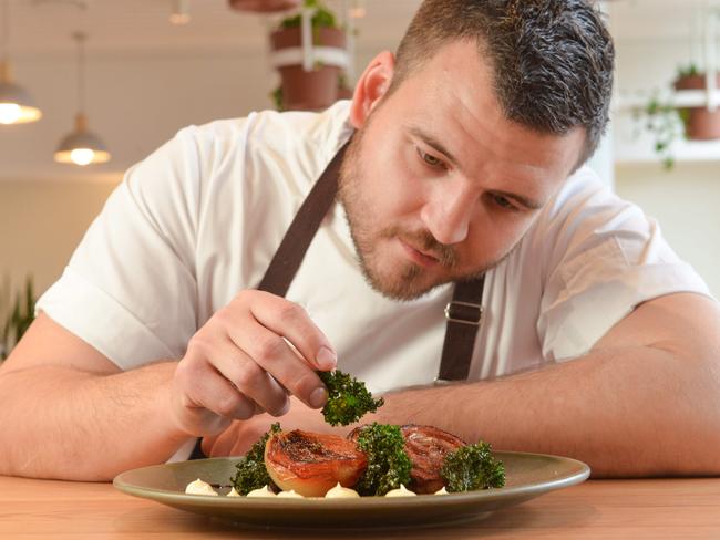 Executive chef Brent Potuszynski puts the finishing touches on lamb breast with roasted onion and crispy kale. Photo: AAP Image/ Brenton Edwards