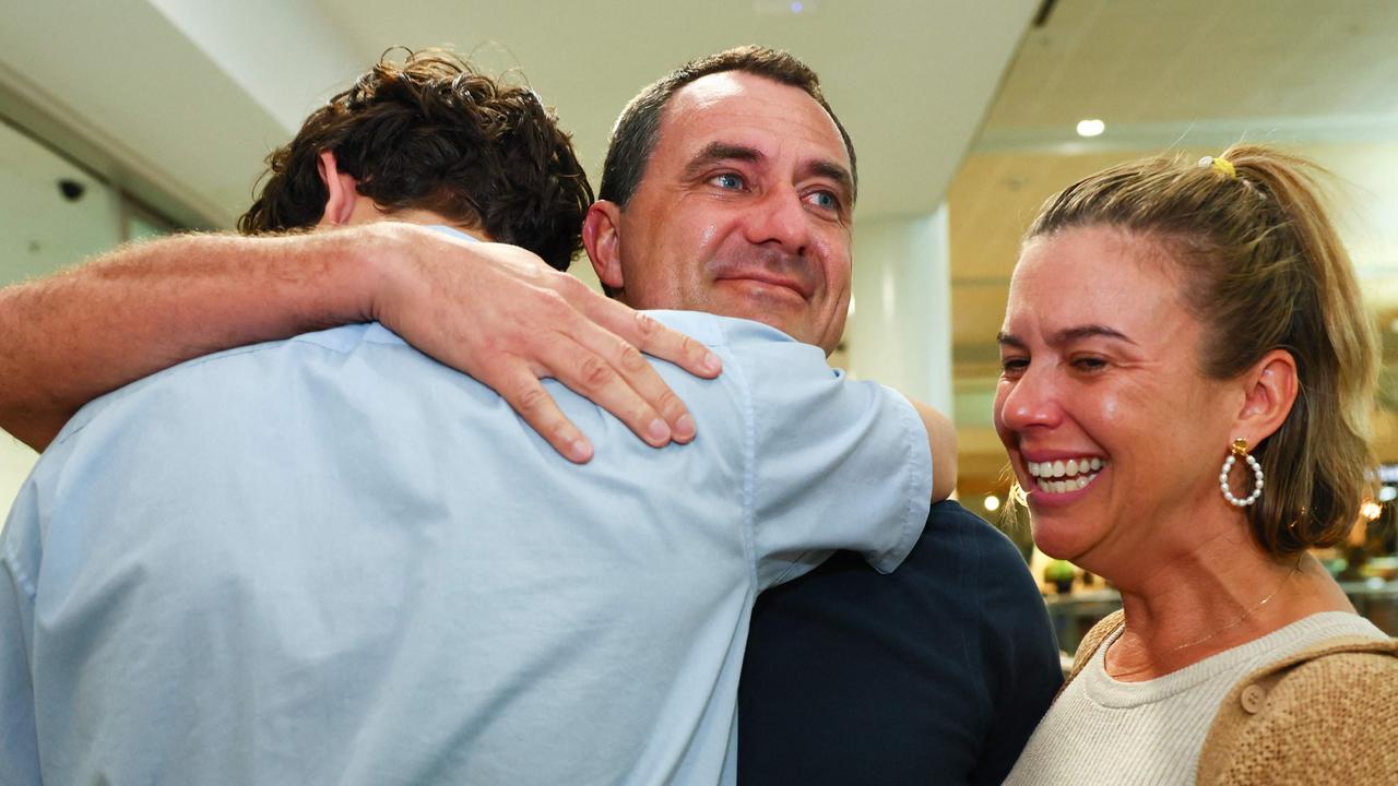 Chris Salmon (C) is greeted by his wife Marney (R) and his son Freddy after  he disembarked a flight arriving from Noumea at Brisbane International Airport in Brisbane on May 21, 2024. A military transport aircraft used to evacuate tourists trapped in riot-hit New Caledonia landed in Australia on May 21, the first rescue flight since looting, arson and deadly gunfire enveloped the French Pacific territory eight days ago. (Photo by Patrick Hamilton / AFP)
