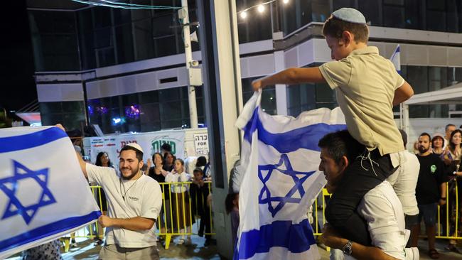 People dance and wave Israeli national flags as they celebrate the news of the death of Hamas leader Yahya Sinwar.