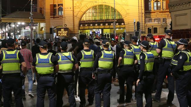 Police keep an eye on a crowd that have gathered on the steps of Flinders Street Station on New years eve in Melbourne. Picture: David Crosling