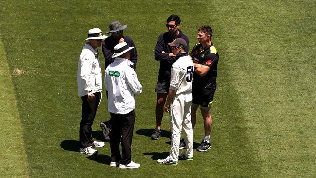 Players and umpires chat about the pitch before going off the ground. Pic: AAP