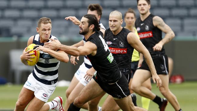 Joel Selwood bursts through a Brodie Grundy tackle.