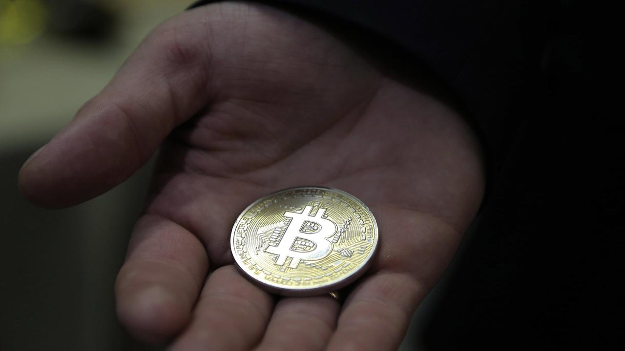 A visitor holds a Bitcoin (virtual currency) souvenir coin, during a webinar by a Russian businessman.