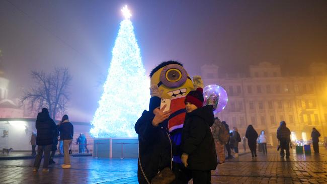 A woman takes a selfie near the Christmas tree in Sophia Square in Kyiv, on December 24, 2024, amid the Russian invasion in Ukraine. (Photo by Anatolii STEPANOV / AFP)