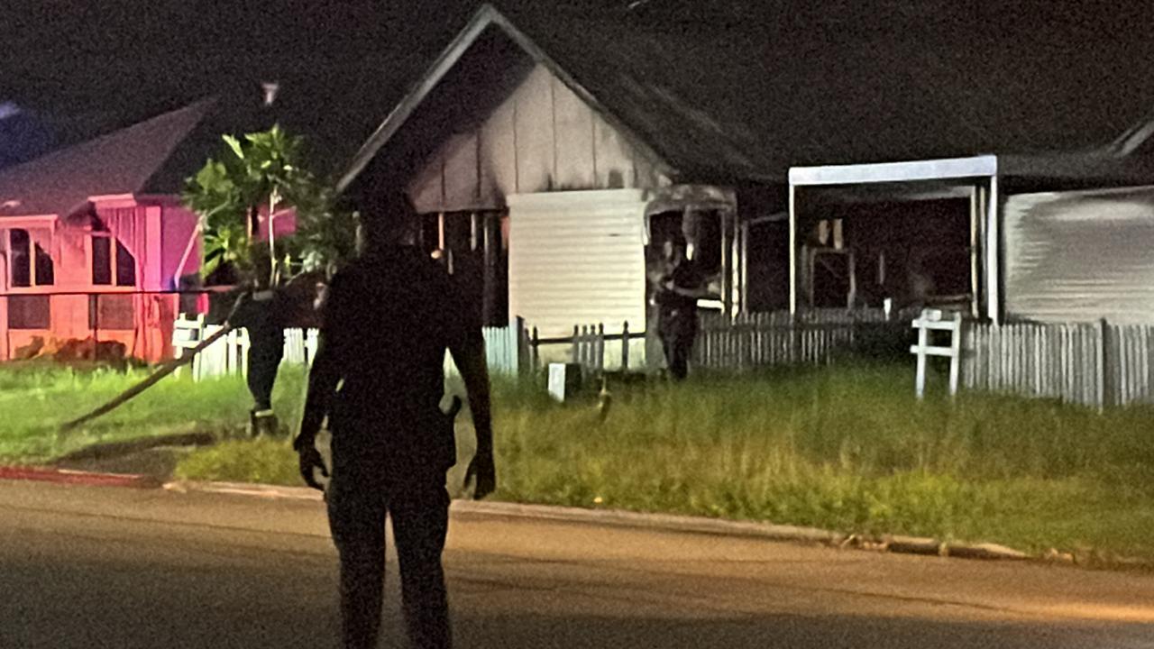 A police officer watches over the scene at a house fire in Ramsay St, Garbutt, which was under control before 9pm.