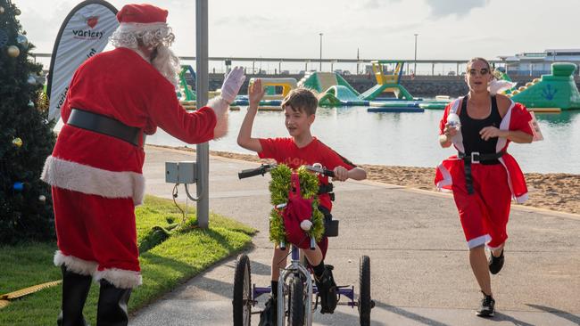 Max Lenoir celebrates the finish line with the santa of the Variety Santa Fun Run 2023, Darwin Waterfront. Picture: Pema Tamang Pakhrin