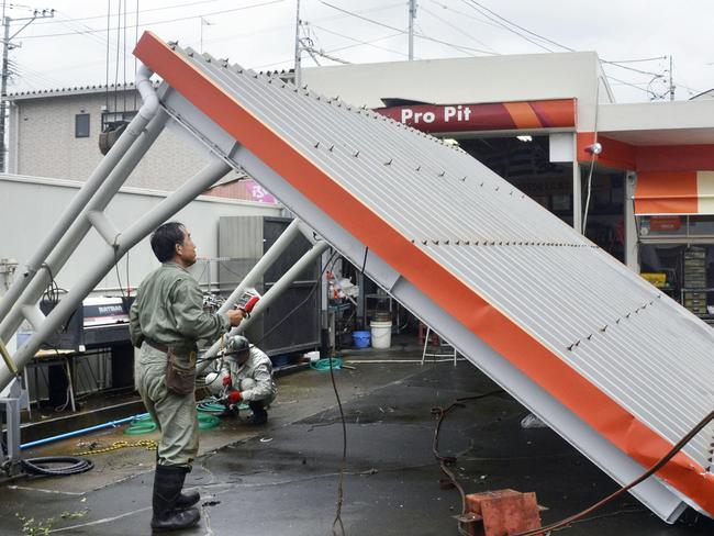 The roof of a car wash topples at a gas station after Typhoon Goni hit Amakusa, Kumamoto prefecture, southwestern Japan, Tuesday, Aug. 25, 2015. The powerful typhoon damaged buildings, tossed around cars and flooded streets in southwestern Japan on Tuesday before heading out to the Sea of Japan. (AP Photo/Kyodo News via AP) JAPAN OUT, MANDATORY CREDIT