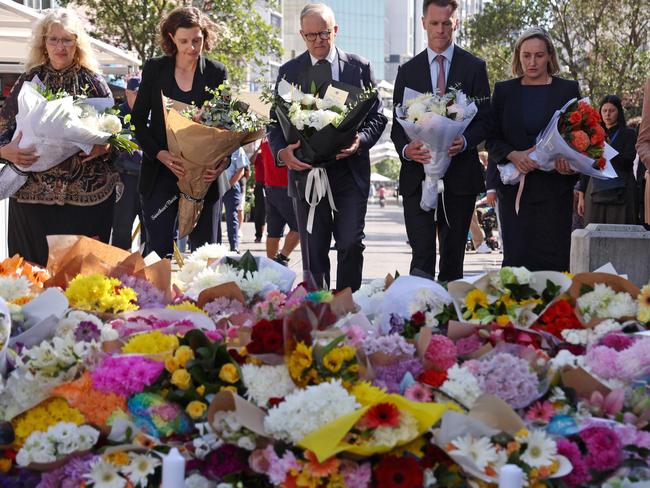 TOPSHOT - Australian Prime Minister Anthony Albanese (C) stands with New South Wales Premier Chris Minns (4th R) and other officials as they prepare to leave flowers outside the Westfield Bondi Junction shopping mall in Sydney on April 14, 2024, the day after a 40-year-old knifeman with mental illness roamed the packed shopping centre killing six people and seriously wounding a dozen others. (Photo by DAVID GRAY / AFP)