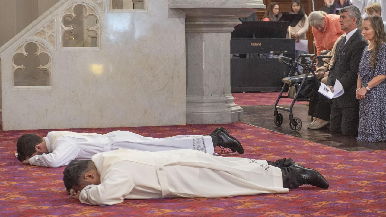 Nathan Webb (at back) and Brian Redondo prostrate themselves before the altar during the ordination ceremony while Nathan’s parents Paul and Fiona Webb look on. Picture: Nev Madsen.