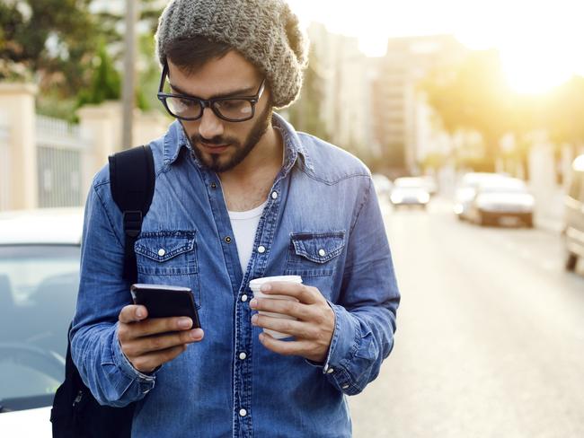 Outdoor portrait of modern young man with mobile phone in the street.