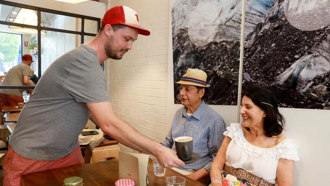 Cortado’s Eugene Baker serves cafe regular Minette, pictured with husband David, a summer latte. (AAP IMAGE / Angelo Velardo)