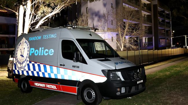 A 50 unit housing complex on Devitt St in Blacktown has gone into full lockdown under 24 hour police guard after 6 residents tested positive to Covid 19. Police set up a van at the rear of the building to keep watch. Picture: Toby Zerna