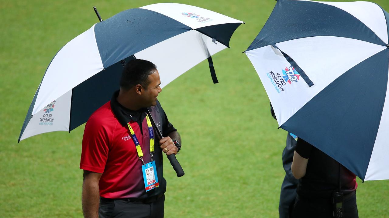 The umpires speak on field as they assess conditions before calling off the game.