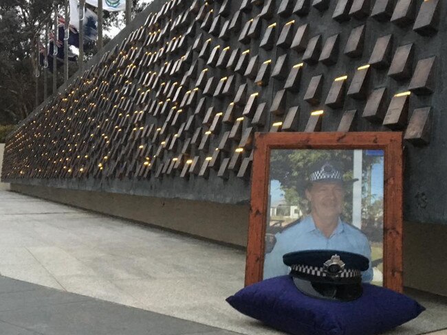 A photo of Queensland Police Senior Sergeant Michael Isles sits near a police memorial. Picture: Facebook