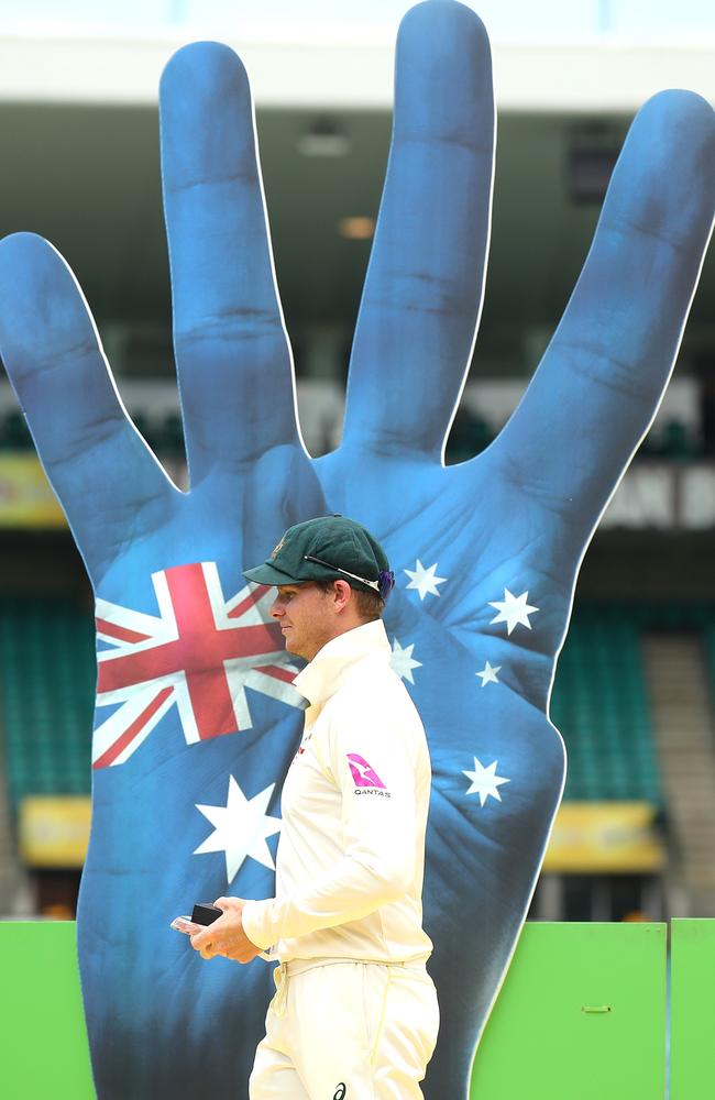 Smith walks past the distasteful backdrop to accept the Ashes Trophy.