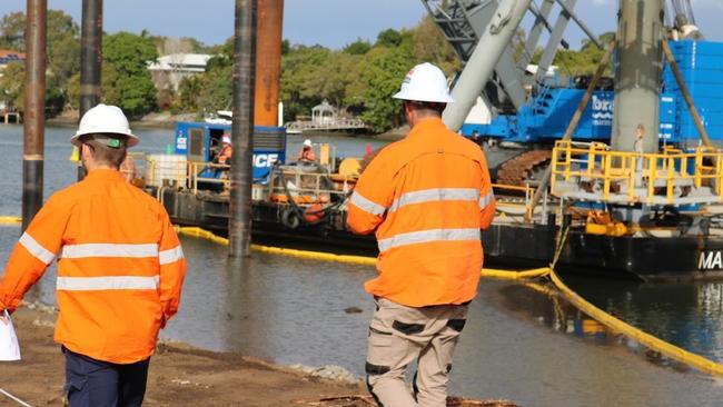 Workers near a barge at the Coomera River, part of building the Coomera Connector.