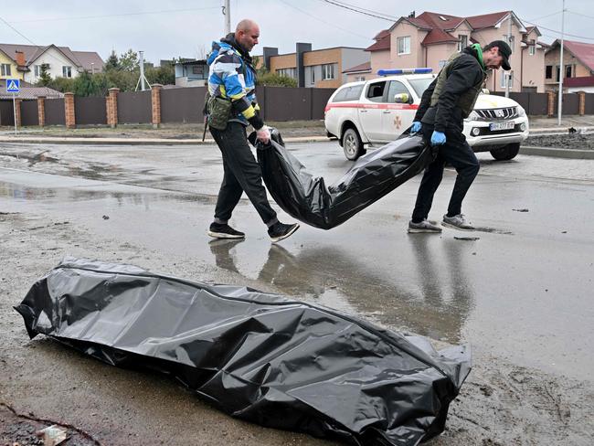 Communal workers carry body bags to a waiting van following Russian shelling of the town of Bucha. Picture: AFP