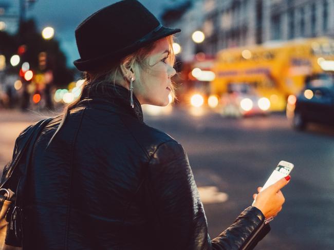 Girl in the city of London using mobile app for taxi calling