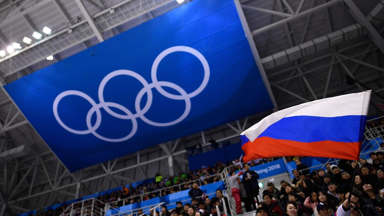 A spectator waves a Russian flag in front of the Olympic Rings. Photo by Brendan Smialowski/AFP